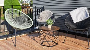 Une terrasse en bois avec trois chaises, une petite table et une plante en pot.