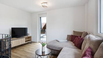 Un soggiorno moderno con una TV a schermo piatto, un tavolino in legno, un divano e una finestra.