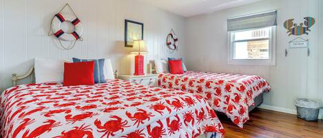 A bedroom with two beds, a ceiling fan, and a window with a view of the outside.