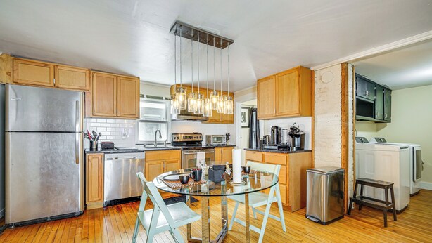 A modern kitchen with wooden cabinets, stainless steel appliances, and a glass dining table. - < 1 Mi to Historic District! Retreat in Bennington (Bennington)