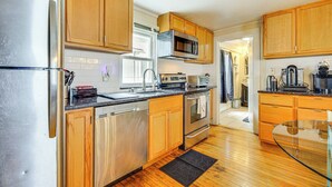 A modern kitchen with wooden cabinets, stainless steel appliances, and a glass dining table. - < 1 Mi to Historic District! Retreat in Bennington (Bennington)