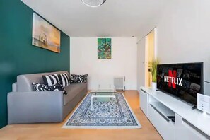 Una sala de estar moderna con un sofá gris, una mesa de centro, un televisor de pantalla plana y una alfombra decorativa.