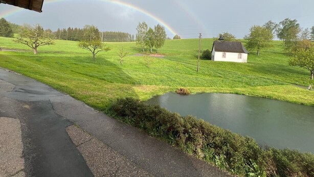 A rural landscape with a house, a pond, and a rainbow. - Holiday Home Ferienhaus am Kapellenhof with Shared Terrace, Shared Garden and Wi-Fi (Triberg im Schwarzwald)