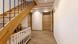 A staircase with wooden steps and metal railings, leading to a room with a white door and a wooden panel wall. - Apartment 'Kapellen Blick' with Mountain View, Shared Terrace and Wi-Fi (Triberg im Schwarzwald)