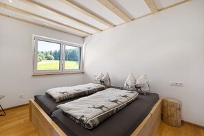 Un dormitorio con un ventanal grande, una cama con ropa de cama estampada y un cabecero de madera.