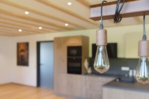 A modern kitchen with wooden cabinets, a countertop, and a hanging light fixture. - Apartment 'Landleben Deluxe' with Mountain View, Shared Terrace and Wi-Fi (Triberg im Schwarzwald)