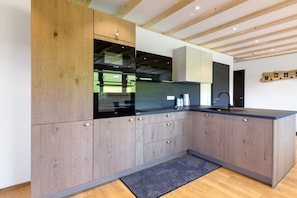 Una cocina moderna con armarios de madera, encimera negra y horno empotrado.