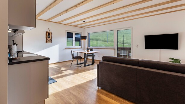 A modern interior with a dining area, sofa, and TV. - Apartment 'Bergpanorama' with Mountain View, Shared Terrace and Wi-Fi (Triberg im Schwarzwald)