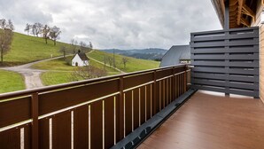 A balcony with a view of a rural landscape, including a white church and rolling hills. - Apartment 'Bergpanorama' with Mountain View, Shared Terrace and Wi-Fi (Triberg im Schwarzwald)