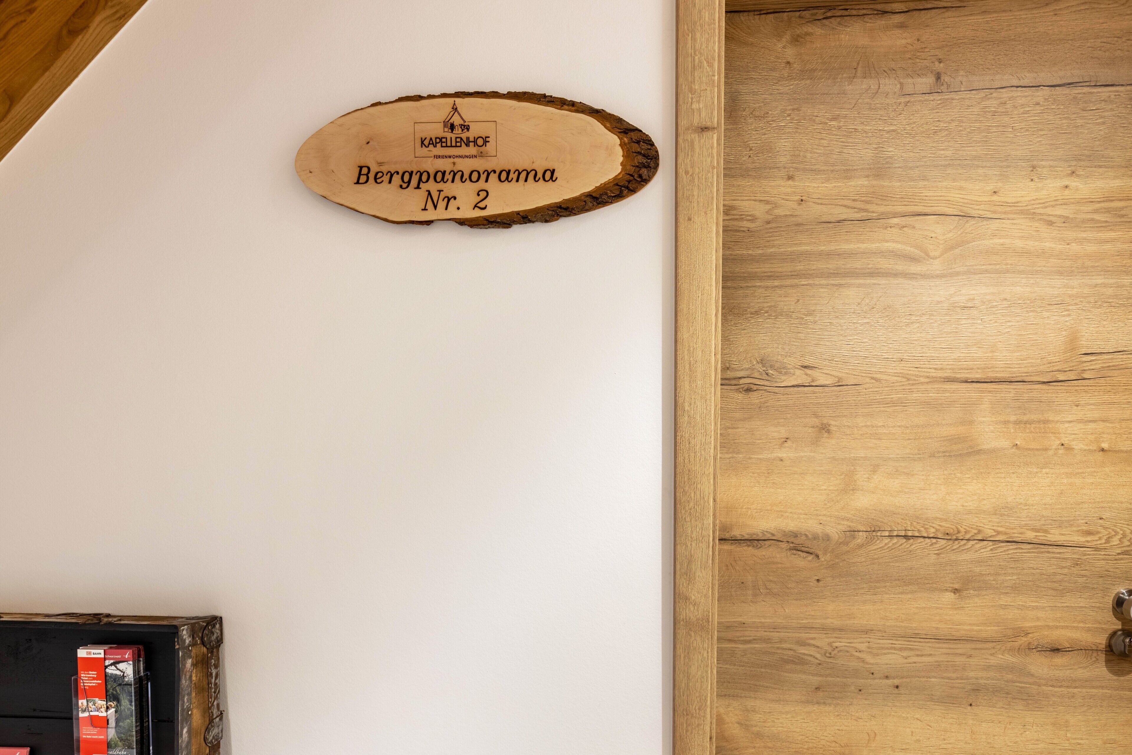 A wooden plaque with 'Bergpanorama Nr. 2' on a white wall.