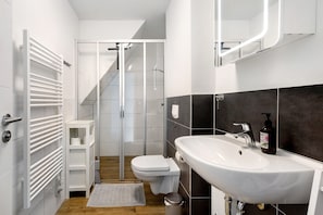A modern bathroom with a white sink, toilet, and glass shower enclosure.