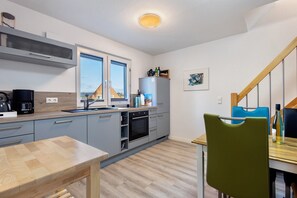 A modern kitchen with a dining area, a built-in oven, and a view through the window.