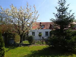 Een huis met een rood pannendak, witte muren en een omheinde tuin.