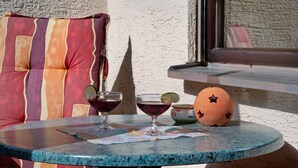 A round table with two glasses of red beverage, a decorative ceramic ball, and a striped cushion.