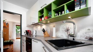 A modern kitchen with a black sink, white cabinets, and green shelves above the countertop.