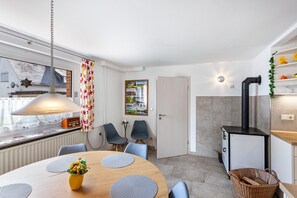 Une cuisine moderne dotée d’une cuisinière intégrée, un coin repas avec une table ronde et des chaises, et une fenêtre donnant sur l’extérieur.
