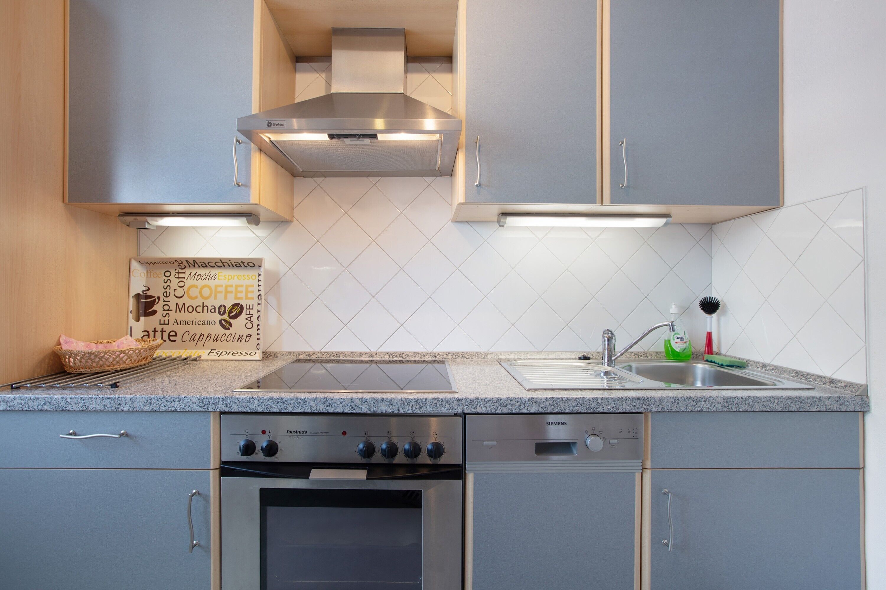 Una cucina moderna con elettrodomestici in acciaio inossidabile, forno integrato e lavastoviglie Siemens.