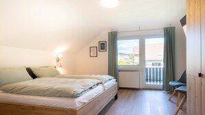 Un dormitorio con una cama de madera, un radiador, una ventana con cortinas y una silla.