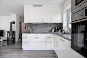 A modern kitchen with white cabinets, a stainless steel stove, and a built-in oven.