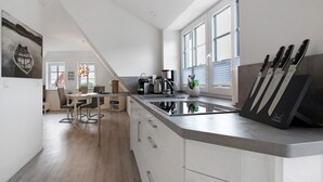 Une cuisine moderne dotée d’un grand îlot central, de meubles blancs et offrant une vue sur l’espace repas.