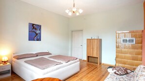 A bedroom with a bed, bedside table, lamp, wooden floor, and a painting on the wall.