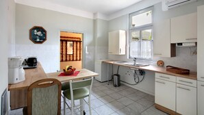 A kitchen with a wooden countertop, white cabinets, a sink, and a window.
