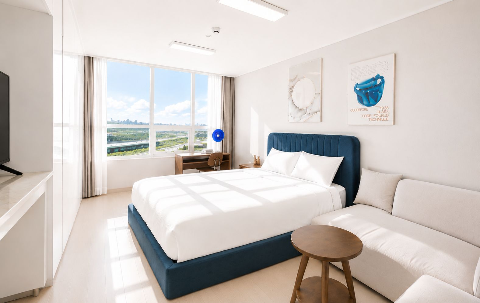 Una camera d'albergo moderna con un letto grande, un divano, una scrivania e una televisione.