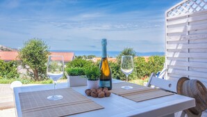 A table set outdoors with a bottle of wine, two glasses, and some nuts. - Trilo Vista Mare-residence La Smeralda (Castelsardo)