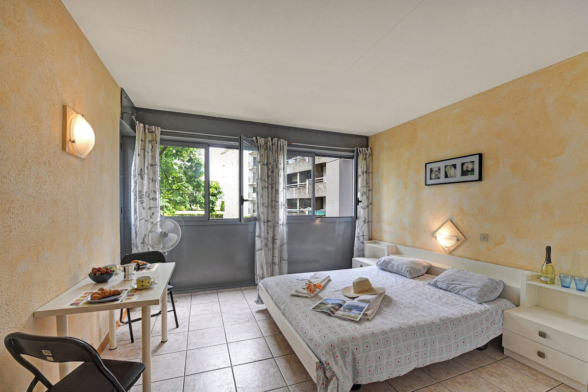 Une chambre à coucher avec un lit, une table de chevet et une fenêtre avec des rideaux.