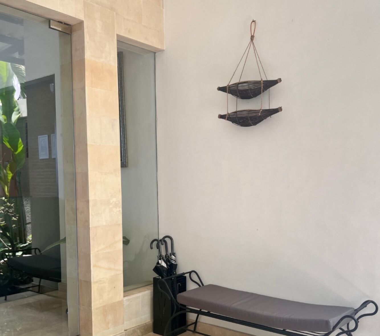Une pièce comprenant un banc, une balance suspendue et une porte vitrée donnant sur un autre espace.