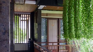 A modern interior with a wooden floor, a balcony with a metal railing, and a view of greenery outside. - Casa Verde Guesthouse (Mengwi)