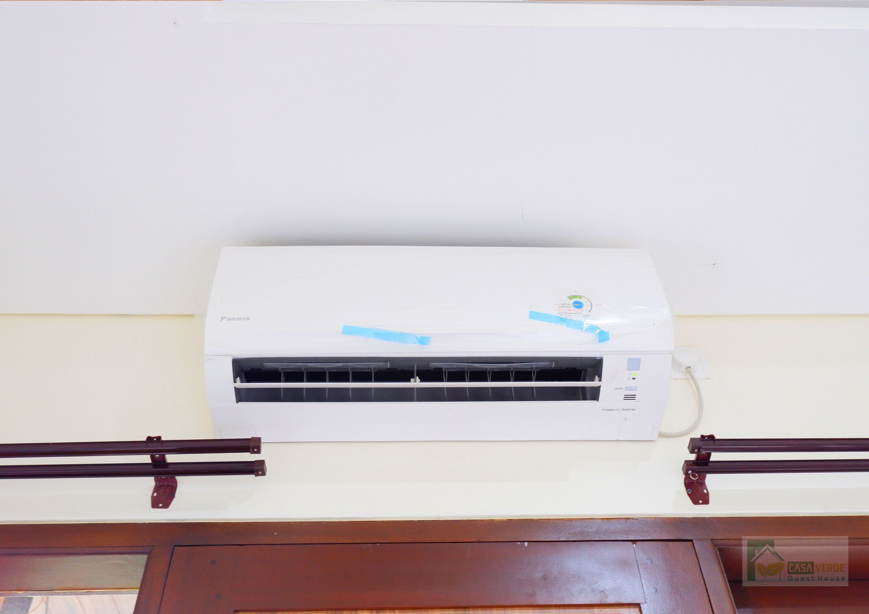 A white Daikin air conditioner mounted on a wall above a wooden door.