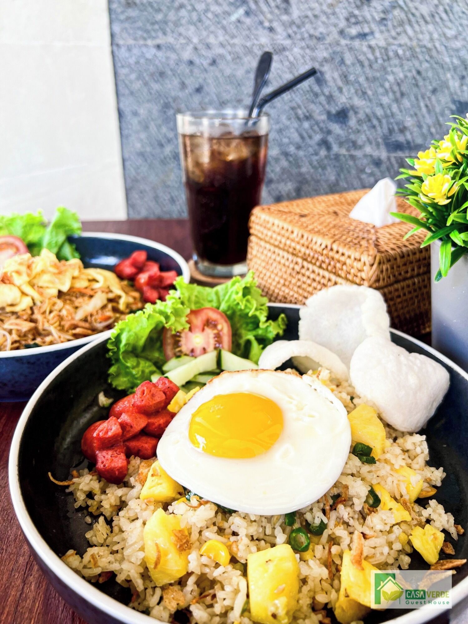 A bowl of fried rice with egg, vegetables, and sausage.