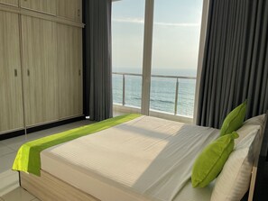 A bedroom with a bed, a view of the sea, and a wardrobe.