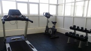 Un gimnasio con cintas de correr, elípticas y un estante de mancuernas.