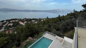 A rooftop pool with a clear view of a lake and distant mountains.