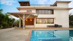 A modern two-story house with a swimming pool, large windows, and a covered patio area. - O NEST By The Beach  (Murud)