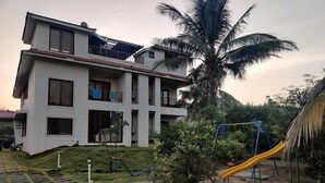 A multi-story residential building with a paved driveway and a playground with a slide. - O NEST By The Beach  (Murud)