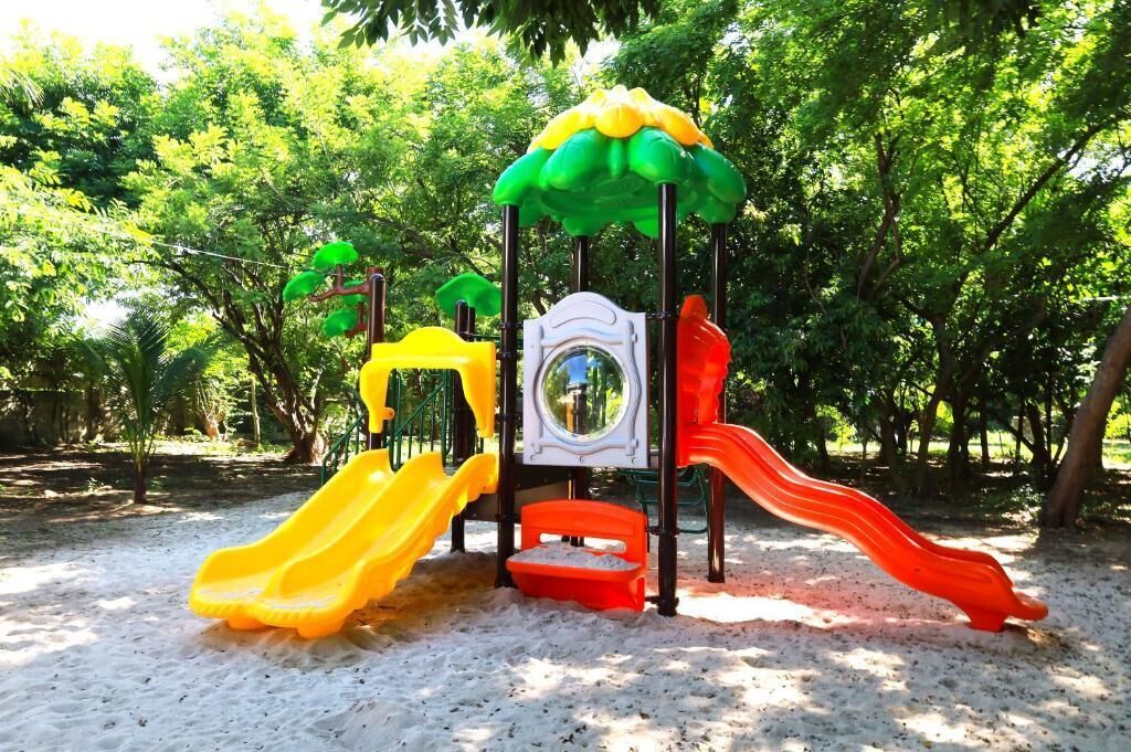 A playground with slides and climbing structures surrounded by trees.