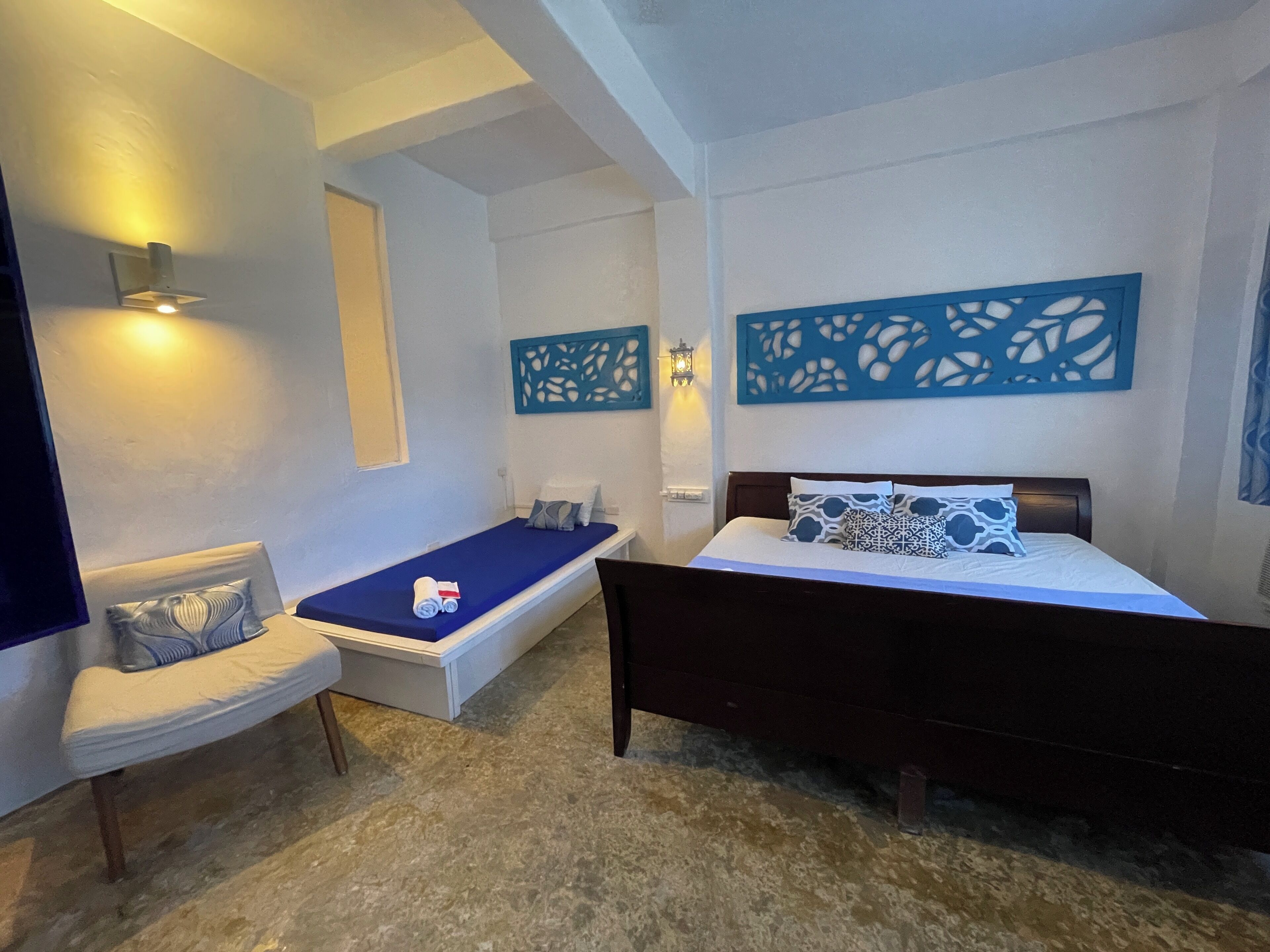A bedroom with a bed, a small sofa, a window, and decorative wall panels.