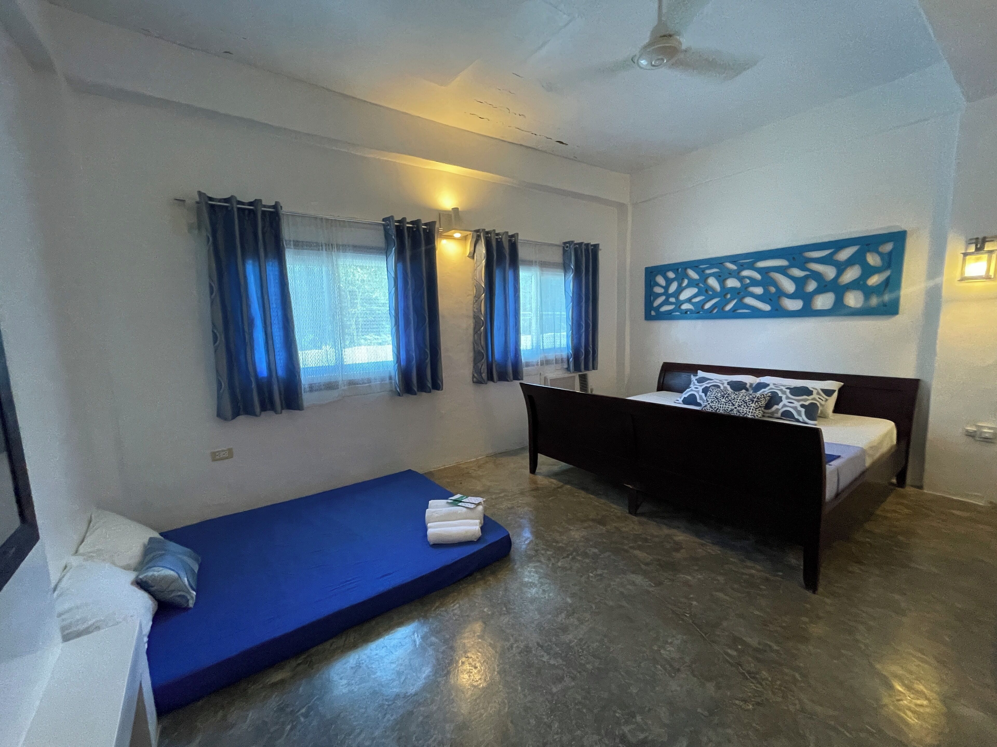 A bedroom with a bed, a blue mattress, and a small sofa.