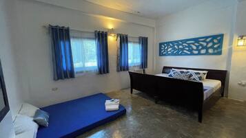 A bedroom with a bed, a blue mattress, and a small sofa.