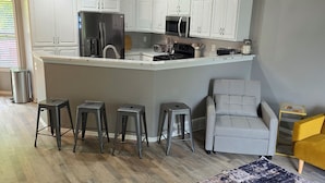 A modern kitchen with white cabinets, stainless steel appliances, and a bar stool seating area. - 3-BR vacation home with 2 spacious entertaining areas: Sleeps 11, 4 miles to DT (Sioux Falls)