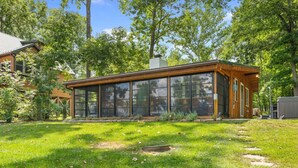 A modern house with large glass windows, a wooden deck, and a well-maintained lawn. - Heron Hideout: Shenandoah Riverfront Retreat! (Luray)