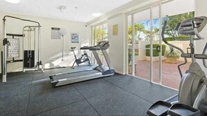Une salle de remise en forme équipée d’un tapis de course, d’un vélo elliptique et d’un vélo d’appartement.