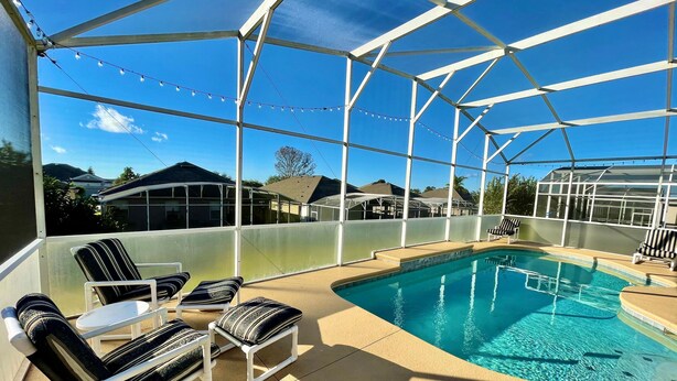A covered outdoor pool area with lounge chairs and a clear view of the surrounding neighborhood.