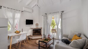 A modern living room with a fireplace, a dining area, and a sofa. - Peaceful Villa at Apanema Mindfulness Lefkada (Sfakiotes)