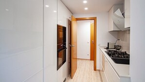 A modern kitchen with white cabinets, a built-in oven, and a gas stove.