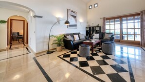 A spacious living area with a checkered floor, a black leather sofa, a coffee table, and a floor lamp. - Villa Endless Summer - Pool and BBQ By LVH (Playa Blanca)