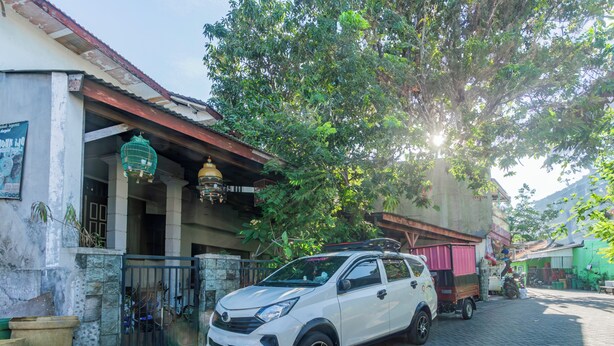 A white SUV parked in front of a building with a tiled roof and a green awning. - OYO Life 94040 Agung Home Stay (Surabaya)